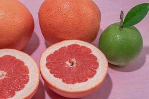 fruits sains bonne nourriture pamplemousse sur table rose. photo