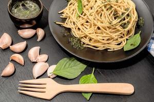 pâtes au pesto dans une assiette sur fond de bois noir cuisine italienne. photo