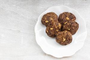 biscuits au chocolat noix de cajou raisins secs dans une assiette sur une table en bois blanc. photo