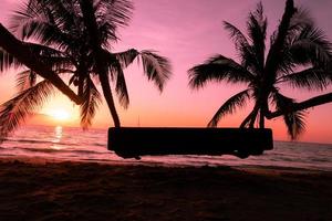 balançoire en bois avec palmier sur la plage tropicale coucher de soleil sur la mer pour voyager en vacances relax tim photo