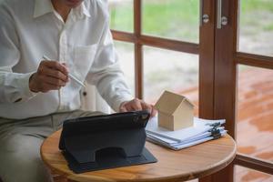 comptable, homme d'affaires, agent immobilier, homme d'affaires remettant une maison modèle aux clients ainsi que des documents de calcul des intérêts de la maison que les clients doivent signer. photo