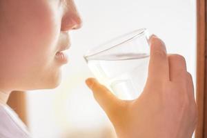 gros plan fille buvant de l'eau à température ambiante propre en été chaude journée photo