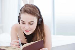 belle fille adolescente se détendre à la maison pour lire un livre et écouter de la musique photo