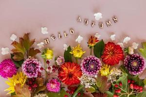 une carte festive, un fond d'écran, un fond d'automne de fleurs de jardin coupées colorées. notion florale. texte composé de lettres en bois - bonjour l'automne. photo