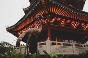 une pagode au centre d'un quartier chinois avec une statue de cigogne brune. photo