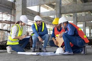 réunion et conseil d'une équipe d'ingénieurs, d'architectes, d'entrepreneurs et de contremaîtres sur le chantier de construction avec plan d'étage pour l'industrie du projet de développement immobilier et le concept de chronologie du logement photo