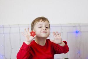 un garçon mignon est assis sur le lit et regarde une tablette. drôle d'enfant souriant. photo