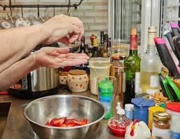 le chef sale des fraises tranchées pour le dessert dans la cuisine de la maison photo