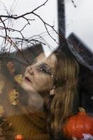 femme sorcière effrayante à l'extérieur de la fenêtre sur le fond des décorations d'halloween. mascarade, fête d'halloween photo