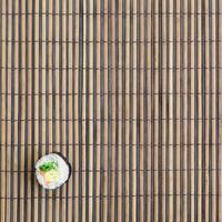 le rouleau de sushi est posé sur un tapis de couture en paille de bambou. cuisine asiatique traditionnelle. vue de dessus. minimalisme à plat tourné avec espace de copie photo