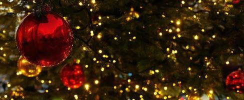 bannière de noël avec espace de copie et scintille pour carte de voeux. branche de sapin avec boules rouges, lumières jaunes festives et bokeh. contenu parfait pour les bannières publicitaires, les cartes-cadeaux ou les projets créatifs. photo