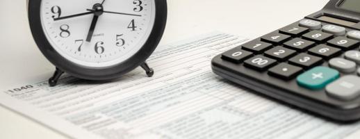 formulaire d'impôt avec horloge, stylo et calculatrice sur fond blanc. notion d'entreprise. photo