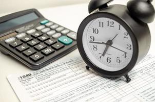 formulaire d'impôt avec horloge, stylo et calculatrice sur fond blanc. notion d'entreprise. photo