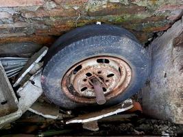 vieilles jantes de voiture, plates et fissurées, rouillées à travers le mur de briques. photo