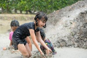 les petites filles s'amusent à jouer dans la boue dans les champs communautaires photo