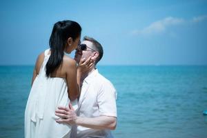 un jeune homme blanc demande à une fille asiatique de se marier avec une bague en diamant sur une plage photo