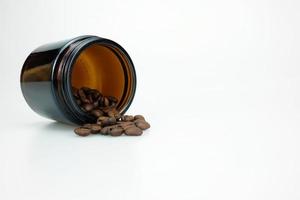Grain de café arabica dans un bocal en verre brun sur fond de studio blanc avec espace de copie pour le texte. photo
