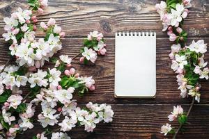 fleurs de sakura sur un fond en bois rustique foncé avec un cahier. fond de printemps avec des branches d'abricot en fleurs et des branches de cerisier photo