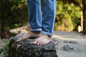 quelqu'un portant un jean et pas de chaussures se tient sur le rocher à la cascade. photo