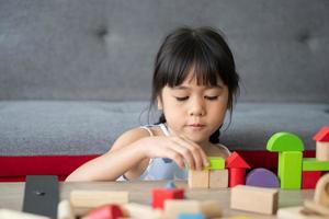 jolie petite fille asiatique jouant avec des blocs de jouets colorés, les enfants jouent avec des jouets éducatifs à la maternelle ou à la garderie. le jeu créatif du concept de développement de l'enfant, enfant en bas âge dans la pépinière. photo