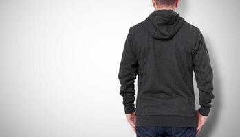 homme en sweat-shirt noir, vue arrière de hoodies noirs. fond gris photo