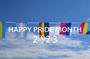 'happy pride month' sur les drapeaux bluesky et arc-en-ciel tenant à la main, fond de coucher de soleil, concept pour les célébrations lgbt du mois de la fierté, juin, dans le monde entier. photo