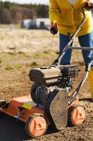 une villageoise utilise un aérateur pour la scarification et l'aération de la pelouse ou du pré photo