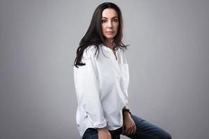 beau mannequin d'âge moyen portant une chemise blanche et un jean dans un studio photo