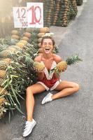 jeune et heureuse femme avec un tas d'ananas sur le marché thaïlandais local photo