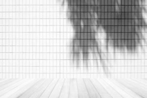 mur de carreaux blancs avec ombre de feuilles de noix de coco et plancher en bois, adapté à la toile de fond, à l'affichage et à la maquette de présentation de produits. photo