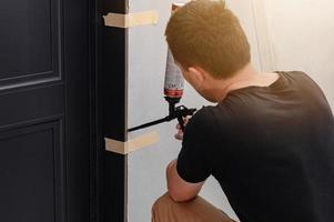 l'utilisation de mousse de montage avec un pistolet pulvérisateur dans les travaux de construction, l'installation de portes intérieures. photo