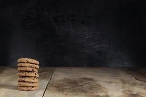 pile de biscuits au chocolat sur une table en bois sur fond noir photo