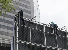 les travailleurs escaladent les structures des panneaux d'affichage pour installer des panneaux d'affichage photo