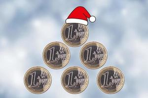Sapin de Noël. les pièces d'un euro sont empilées sous la forme d'une pyramide et d'un chapeau de père noël sur un arrière-plan flou du nouvel an. photo