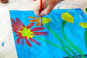 l'enfant dessine une image lumineuse. grands traits de peinture sur papier. photo