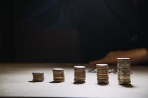 homme d'affaires détenant des pièces de monnaie mettant en verre. concept d'économiser de l'argent pour la comptabilité financière photo