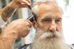 coiffeur faisant une coupe de cheveux élégante pour un beau vieil homme photo