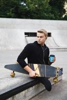 Un gars handicapé avec une tasse de café avant de rouler en longboard dans un skatepark photo