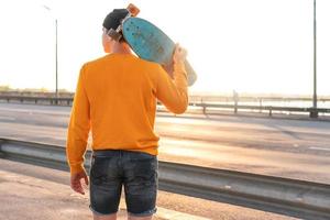 jeune homme avec un longboard sur un pont au coucher du soleil photo