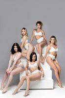 groupe de femmes différentes portant de la lingerie blanche sur fond gris. photo