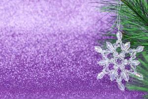 flocon de neige en cristal sur le sapin de noël. flocon de neige sur fond violet. photo