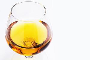 Petit verre rempli d'un cognac sur fond blanc photo