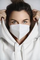 jeune femme portant un sweat à capuche blanc et un masque respiratoire ffp2 photo
