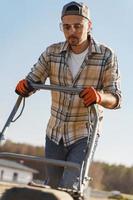 homme utilisant une machine d'aération pour la scarification et l'aération de la pelouse ou du pré photo