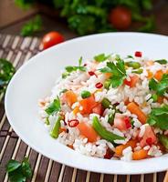 riz sain appétissant avec des légumes dans une assiette blanche sur un fond en bois. photo