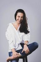 belle femme d'âge moyen portant une chemise blanche et un jean en studio photo