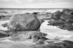 grosse pierre en noir et blanc prise dans l'eau sur la plage dans la mer. danois photo
