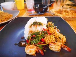 fruits de mer épicés avec riz au jasmin dans un plat gris sur une table en bois photo