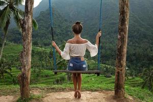 femme sur des balançoires avec une belle vue sur les rizières en terrasses de bali. photo