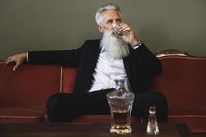 homme âgé beau et barbu buvant du whisky photo